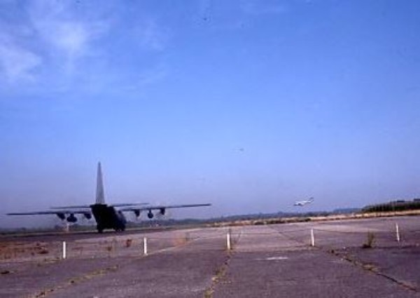 .Le C 130 se dirige vers le bout de piste ou un avion de ligne est en procédure d' atterrissage 